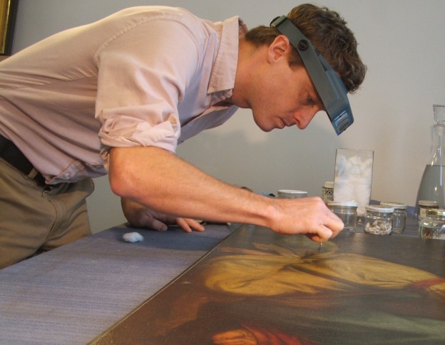 Tim Neill restoring a painting on canvas