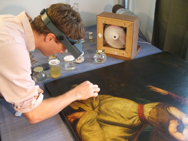 Tim Neill cleaning a painting on canvas